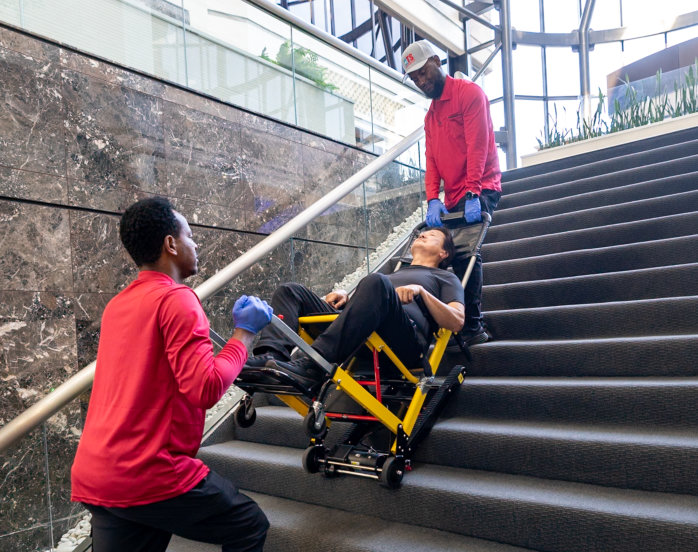 A man carefully pushes a wheelchair down a flight of stairs