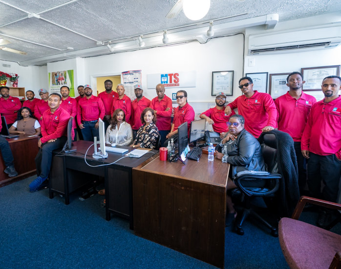 A group of people wearing red shirts smiles and poses together for a photo